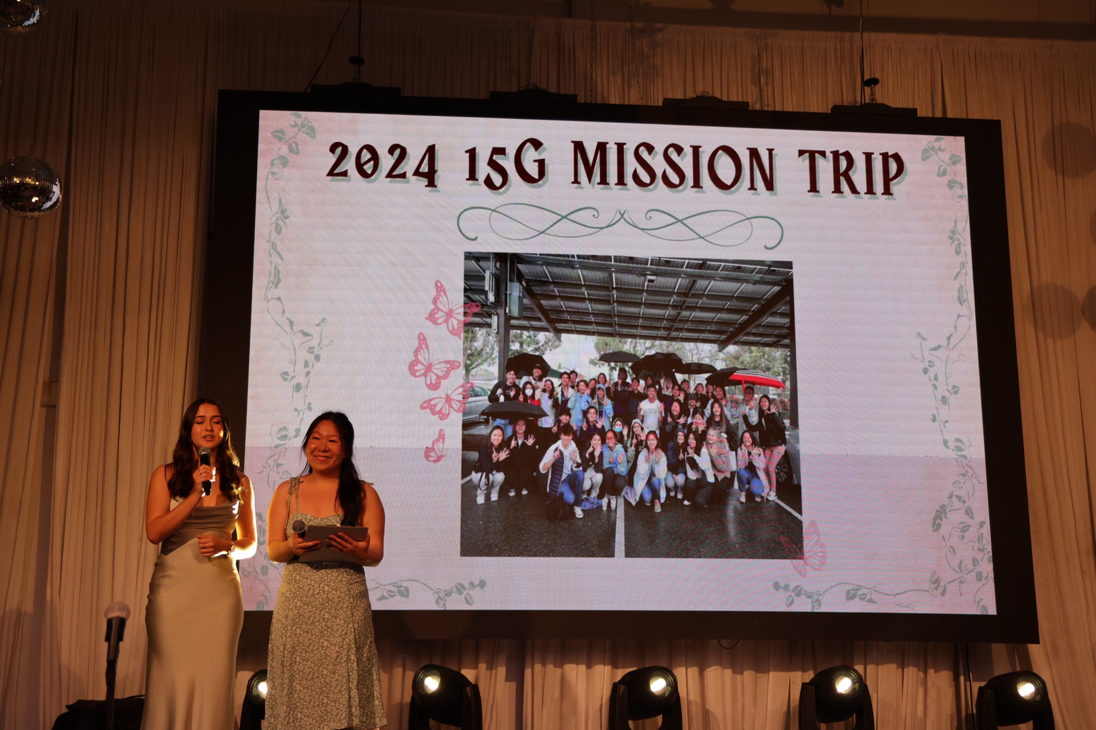 Student presenters speaking beside the 2024 mission presentation at the gala