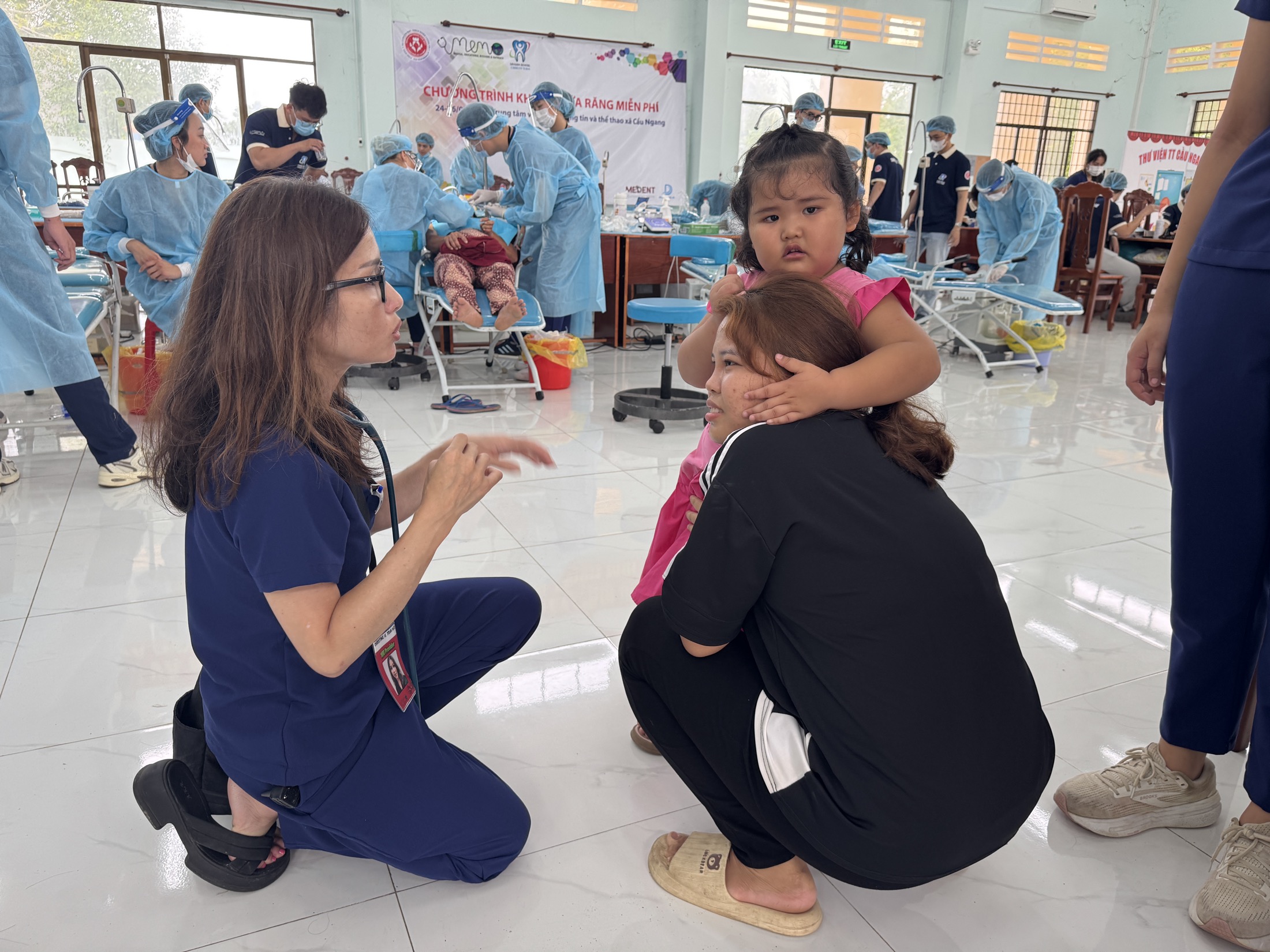 Volunteer speaking with a child and caregiver inside the mission clinic